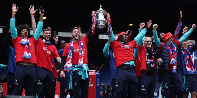 crystal-palace-s-joel-ward-and-marc-guehi-hold-the-trophy-with-teammates-during-the-victory-celebrat.jpeg